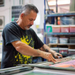 Ein Mann beim bedrucken eines T-Shirts mit Siebdruck